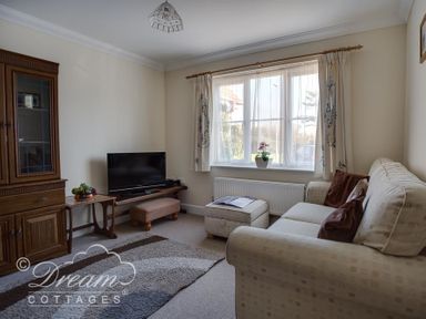 A living room with a sofa ottoman and television cabinet at Bridge Apartment in Weymouth