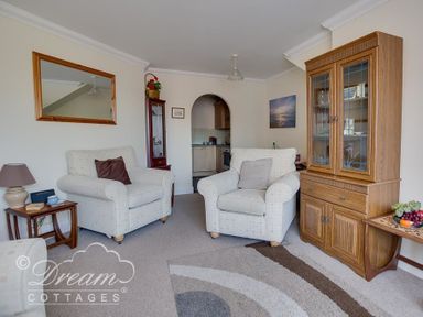 A living room with two armchairs a wooden cabinet and a side table with a lamp at Bridge Apartment in Weymouth