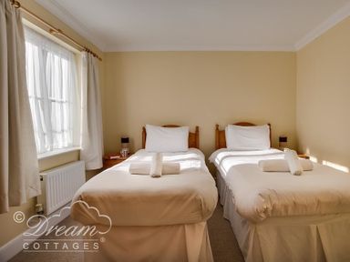 A bedroom with two single beds side by side with white bedding and towels on each bed at Bridge Apartment in Weymouth
