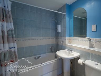 A bathroom with a bathtub shower sink toilet and a mirror at Bridge Apartment in Weymouth
