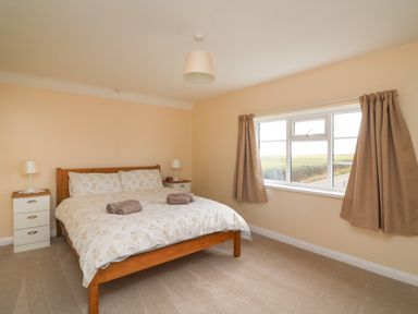 A bedroom with a double bed bedside tables lamps and a window with curtains at Cliff Farm No 2 Cottage Burton Bradstock