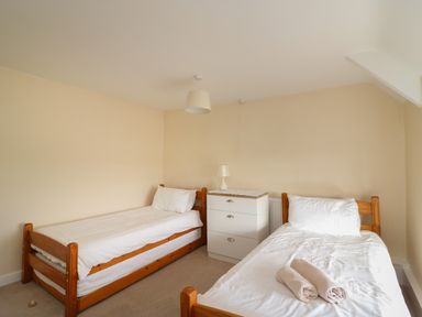 A bedroom with two single beds a white chest of drawers and a lamp at Cliff Farm No 2 Cottage Burton Bradstock