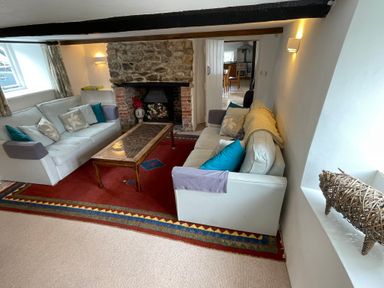 A living room with two sofas a coffee table a stone fireplace and a red rug at Culverwells in Axminster