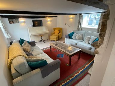 A living room with two sofas a yellow armchair a piano and a red patterned rug at Culverwells in Axminster