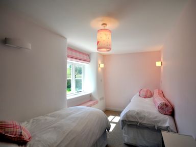 A bedroom with two single beds and a window with pink checkered curtains at Culverwells in Axminster