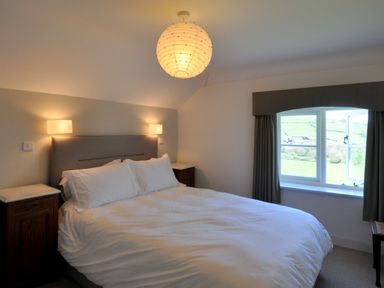 A bedroom with a double bed bedside tables and a window with curtains at Culverwells in Axminster