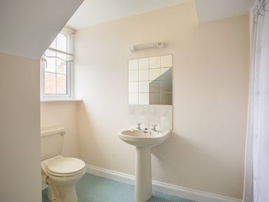 A bathroom with a toilet sink mirror and window at The Doves in Burton Bradstock