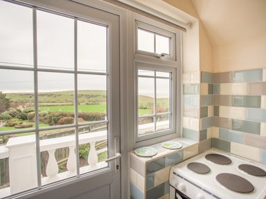 A kitchen corner with a stove next to windows overlooking a garden and field at The Doves in Burton Bradstock