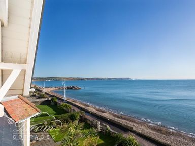 A view of a coastline with a beach road garden and blue sea at Dream View in Greenhill