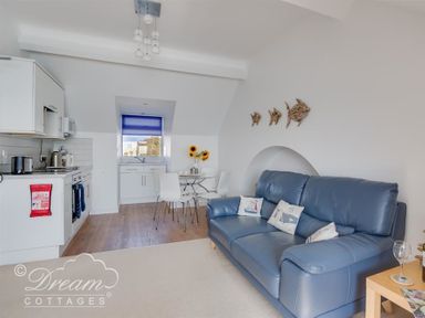 A kitchen and living area with a blue sofa and dining table with sunflowers at Dream View in Greenhill