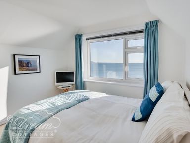 A bedroom with a bed a small TV on a side table and a window with a sea view at Dream View in Greenhill