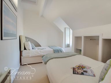 A bedroom with two single beds a wall mirror and open closet spaces at Dream View in Greenhill