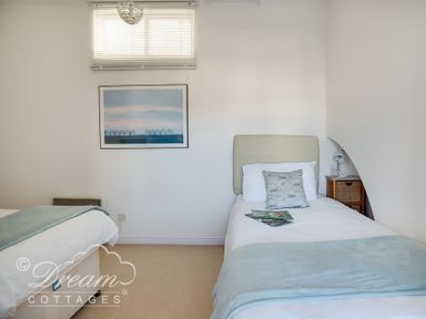 A bedroom with two single beds one with a side table and lamp and a framed picture above at Dream View in Greenhill