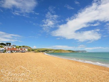 A pebble beach with houses on the left and hills in the background at Dream View in Greenhill