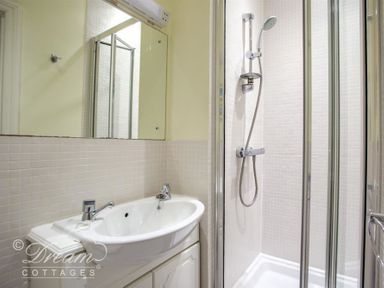 A bathroom with a sink and mirror next to a glass-enclosed shower at Harbour Edge in Brewers Quay Harbour
