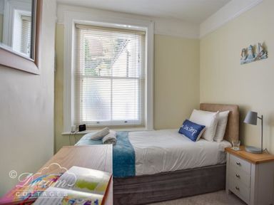 A bedroom with a single bed side table lamp window and chest of drawers at Harbour Edge in Brewers Quay Harbour