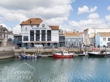 Boats docked in a harbor with buildings including one named Rendezvous in Brewers Quay Harbour