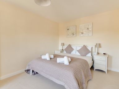 A bedroom with a double bed two bedside tables with lamps and rolled towels on the bed at The Ferns in Weymouth