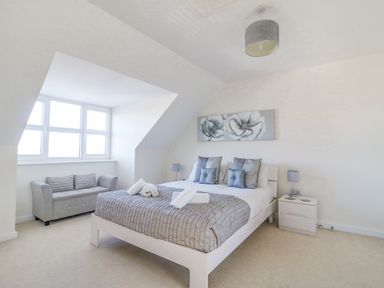 A bedroom with a bed sofa bedside tables and a window at The Ferns in Weymouth