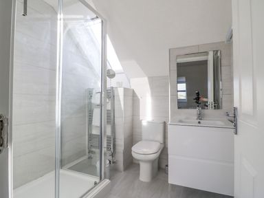 A bathroom with a shower enclosure a toilet a sink with a mirror and a towel rack at The Ferns in Weymouth
