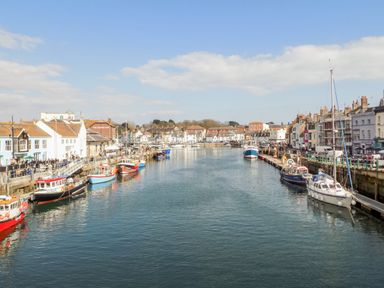 A harbor with boats docked along both sides and buildings lining the waterfront at Brewers Quay Harbour