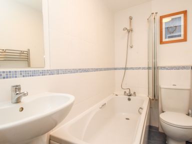 A bathroom with a sink a bathtub with shower a toilet and a framed picture on the wall at Firkin Cottage Brewers Quay Harbour
