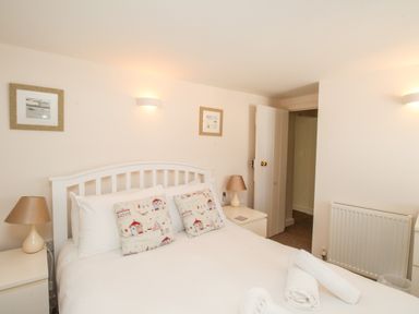 A bedroom with a white bed and two bedside tables with lamps at Firkin Cottage Brewers Quay Harbour