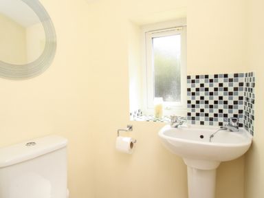 A bathroom with a toilet white sink and a window with mosaic tiles around the sink at Firkin Cottage Brewers Quay Harbour