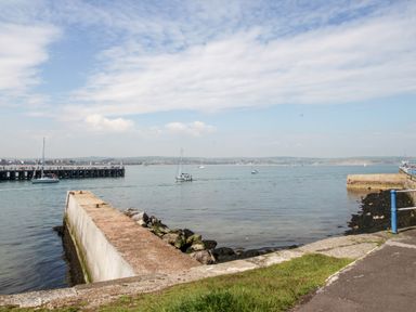 A coastal view with a concrete pier and sailboats on the water at Brewers Quay Harbour
