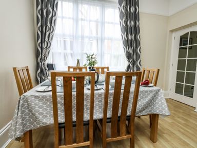A dining room with a wooden table covered by a patterned tablecloth and wooden chairs at Footprint Brewers Quay Harbour