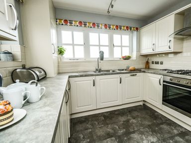 A kitchen with white cabinets a gray countertop a sink an oven and various kitchen items at Footprint Brewers Quay Harbour