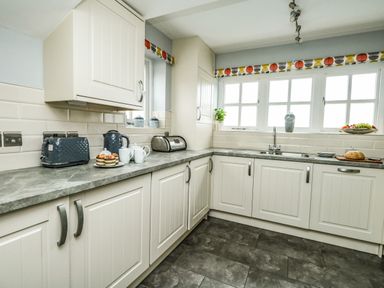 A kitchen with white cabinets a countertop toaster kettle plates fruit bread and a sink at Footprint Brewers Quay Harbour