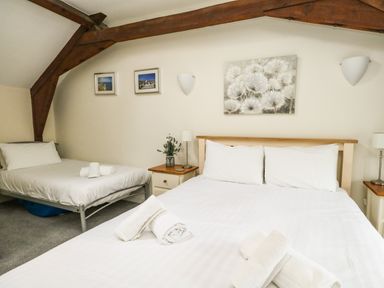A bedroom with two beds white linens bedside tables lamps and wall art at Footprint Brewers Quay Harbour