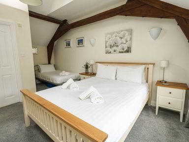 A bedroom with a large bed and a single bed under exposed wooden beams at Footprint in Brewers Quay Harbour