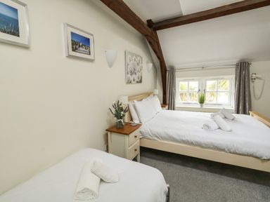 A bedroom with two beds a nightstand with flowers wall art and a window at Footprint in Brewers Quay Harbour