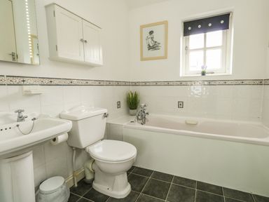 A bathroom with a sink toilet bathtub wall cabinet and a small window at Footprint in Brewers Quay Harbour