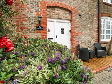 An entrance with white double doors and flowers beside a small patio with two black chairs at Footprint Brewers Quay Harbour