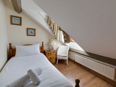 A bedroom with a single bed a wooden nightstand a white chair and a slanted ceiling window at Georges House Brewers Quay Harbour
