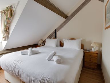 A bedroom with a double bed rolled towels bedside tables lamps and a window with curtains at Georges House in Brewers Quay Harbour