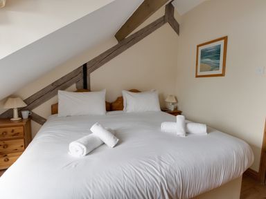 A bedroom with a double bed white linens rolled towels bedside tables lamps and framed artwork at Georges House Brewers Quay Harbour