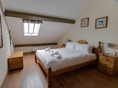 A bedroom with a wooden bed and white bedding under a skylight at Georges House in Brewers Quay Harbour