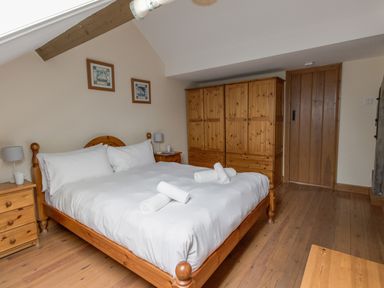 A bedroom with a wooden bed and bedside tables with lamps wardrobes and a wooden door at Georges House Brewers Quay Harbour