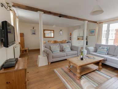 A living room with two sofas a wooden coffee table a dining area and kitchen at George's House in Brewers Quay Harbour