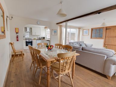 A dining area with a wooden table and chairs next to a kitchen and a living room with sofas at Georges House in Brewers Quay Harbour