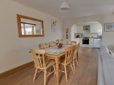 A dining area with a wooden table and six chairs next to a kitchen with white cabinets at Georges House Brewers Quay Harbour