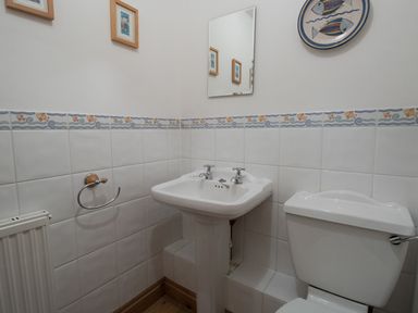 A bathroom corner with a white sink and toilet and decorative tiled walls at Georges House Brewers Quay Harbour