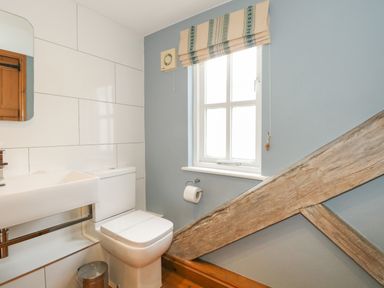 A bathroom with a toilet sink a mirror window and wooden beams at Georges House Brewers Quay Harbour