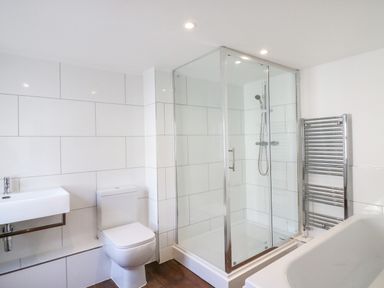 A bathroom with a toilet sink shower enclosure heated towel rail and bathtub at Georges House in Brewers Quay Harbour