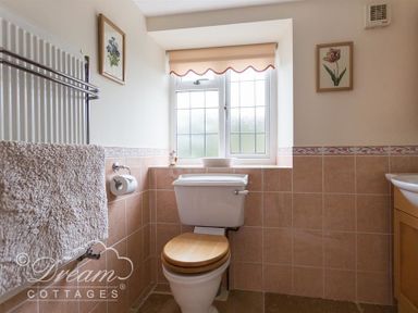 A bathroom with a toilet under a window and a towel on a rack at Grazeland Cottage in Bridport