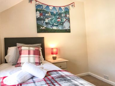 A bedroom with a bed a bedside table with a lamp and a painting above the bed at Guinea Cottage in Brewers Quay Harbour